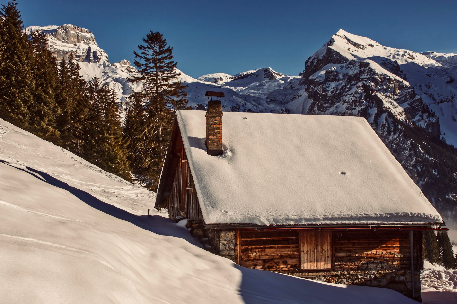 Contemporary wooden alpine cabin in snow covered valley